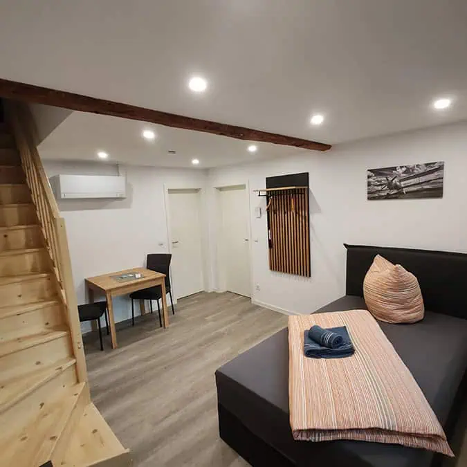 Essbereich mit Tisch und Stühlen in einer modernen Wohnung mit Holztreppe und gemütlicher Einrichtung.